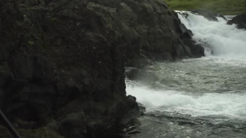 A blonde woman photographing cascading rapids on a mountainside