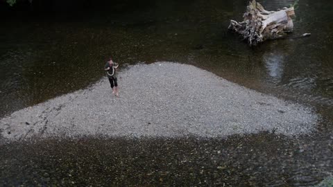 A hiker wades through a shallow river