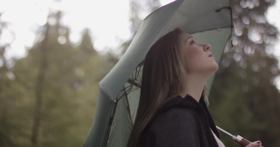 A woman holding an umbrella looks up