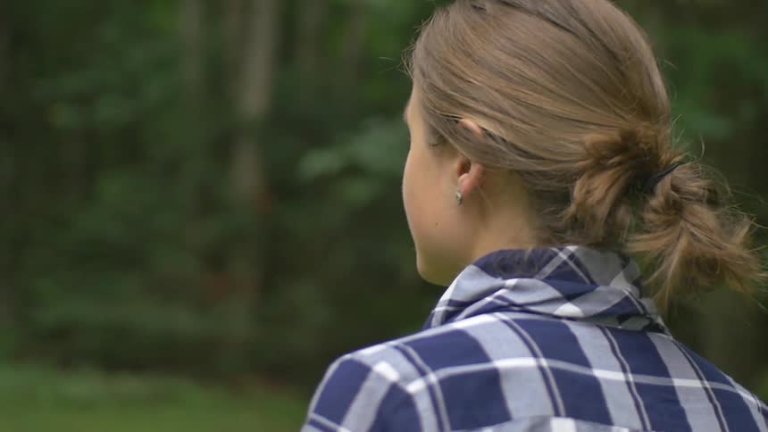 A woman walks amidst green trees