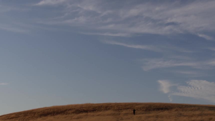 A person traversing a grassy foothill