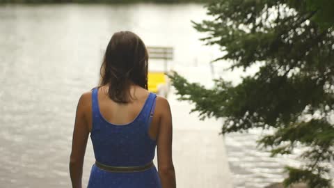 Dark haired woman walks along a dock