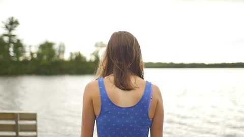 A portrait of woman with swimsuit walks toward the lake water