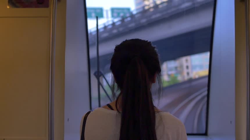 A woman looks out the window of a train