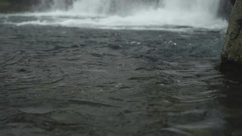 A waterfall gushes into a body of water