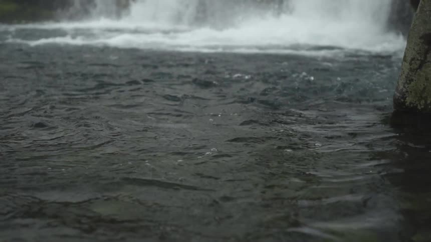 A waterfall gushes into a body of water