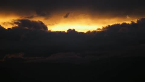 Large dark clouds with the sun shining amber light through them