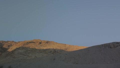 The sun rises over a dirt hill