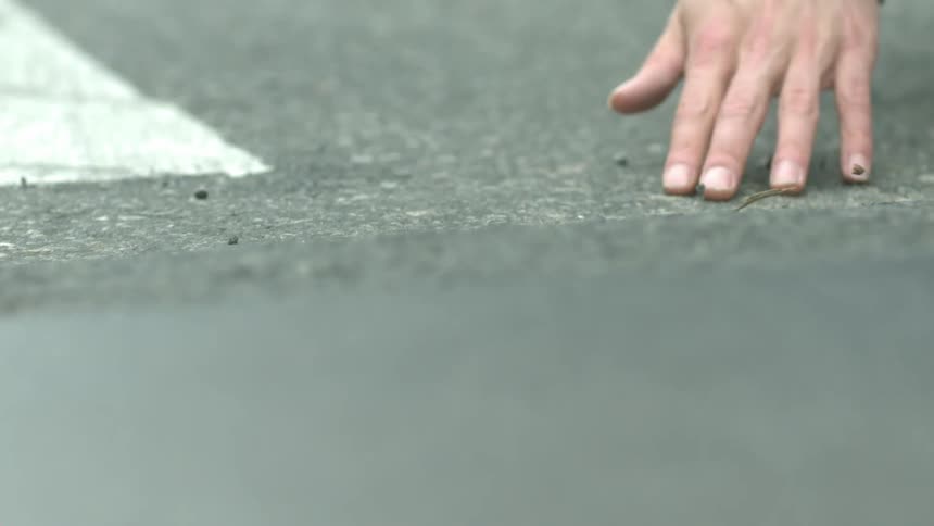 Person dragging their hand across concrete