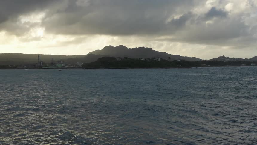 A body of water with  mountains and clouds in the distance
