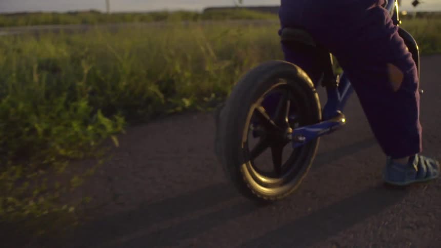 A person rides a bike on a road near grass