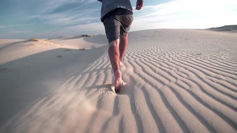 Man running through sandy desert on a sunny day