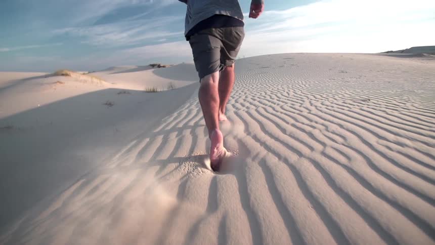 Man running through sandy desert on a sunny day