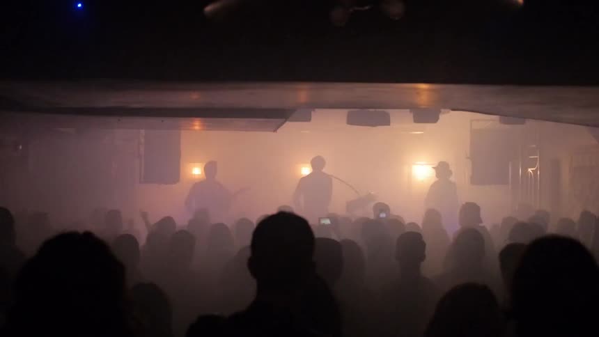 A band is playing to an audience in a small venue