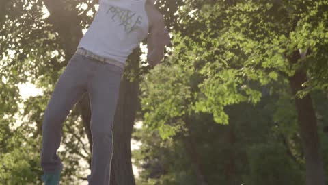 A man wearing a baseball cap doing a cartwheel and flip in the park