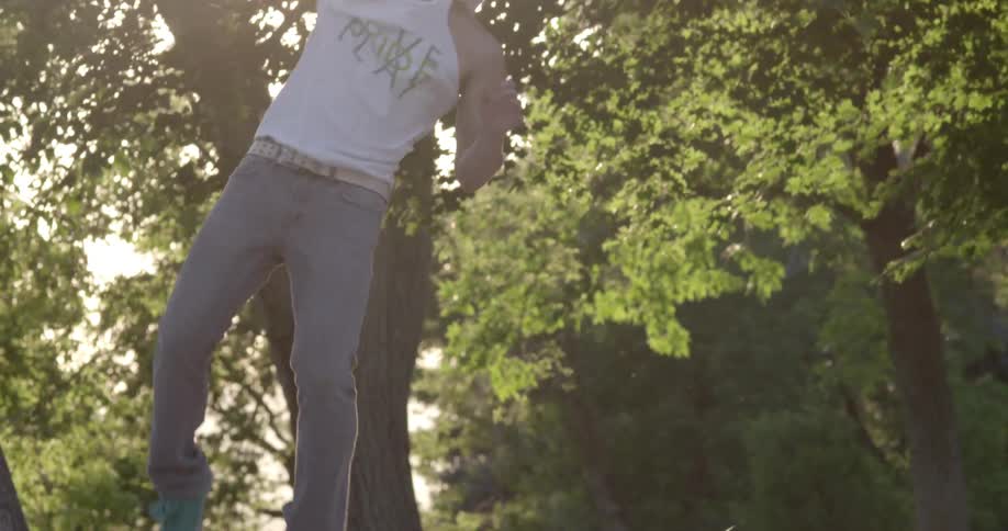 A man wearing a baseball cap doing a cartwheel and flip in the park