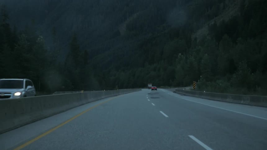 Cars driving up and down a windy road at the bottom of mountains at night