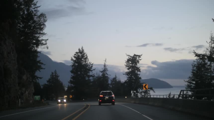 Cars driving along a mountain road at dusk