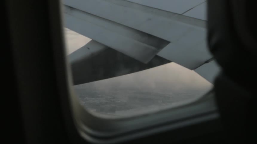 Clouds and land mass viewed from an airplane window mid flight