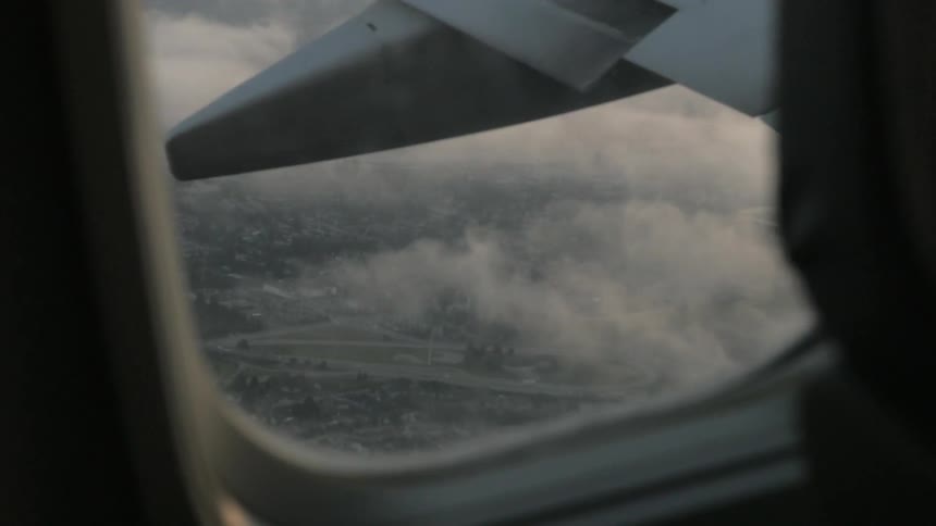Clouds and the city below shown through an airplane window