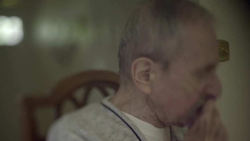 An elderly man adjusts his breathing tube
