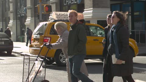 Man and three women walking across a busy street