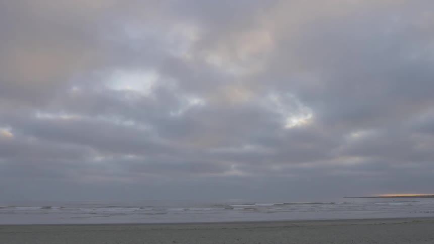 Time lapse of gray clouds over a beach at sunset
