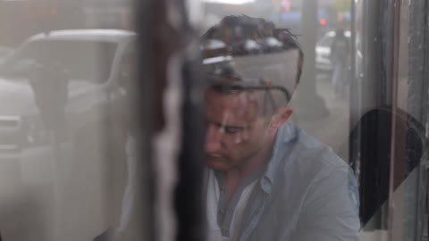 Person behind glass on a city street and writing