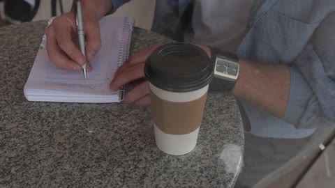 Man sitting at the table writes down in the cafe