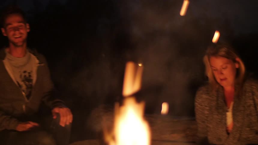 A woman is laughing next to a fire