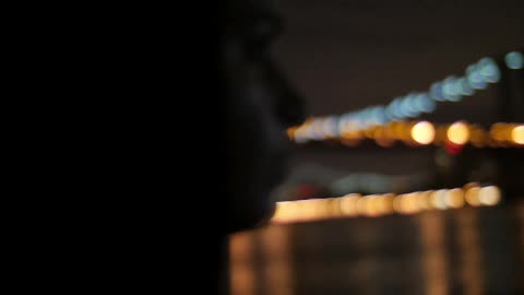 A woman looks at a cityscape at night