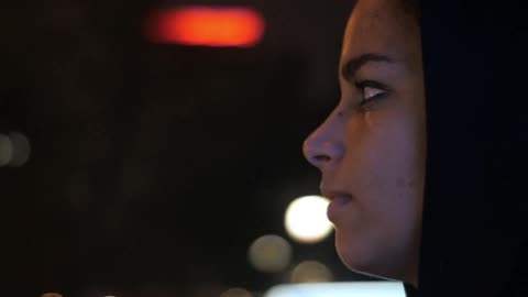 A woman looks around in the city at night