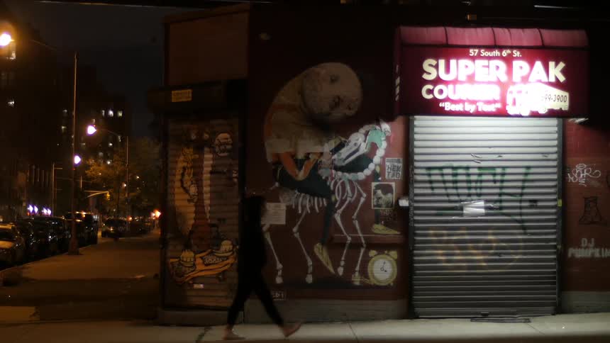 A person walks past a closed business at night