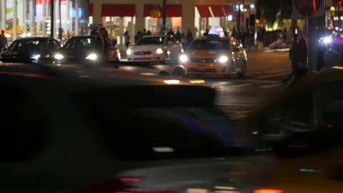 A view of both vehicular and foot traffic at a busy city intersection at night