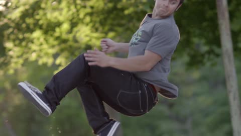 A man jumps and flips around in front of trees