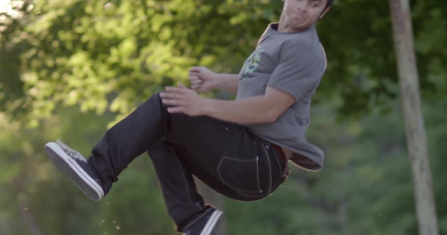A man jumps and flips around in front of trees