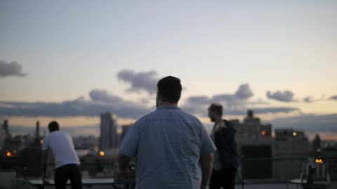 A group of friends stands on the rooftop of the building
