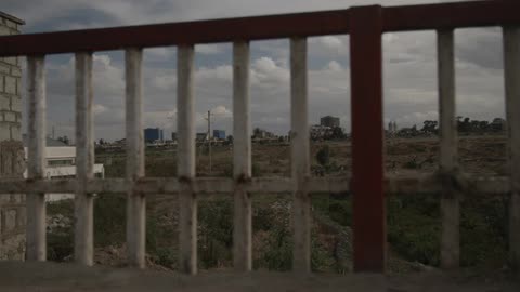 A far away city is shown through a fence