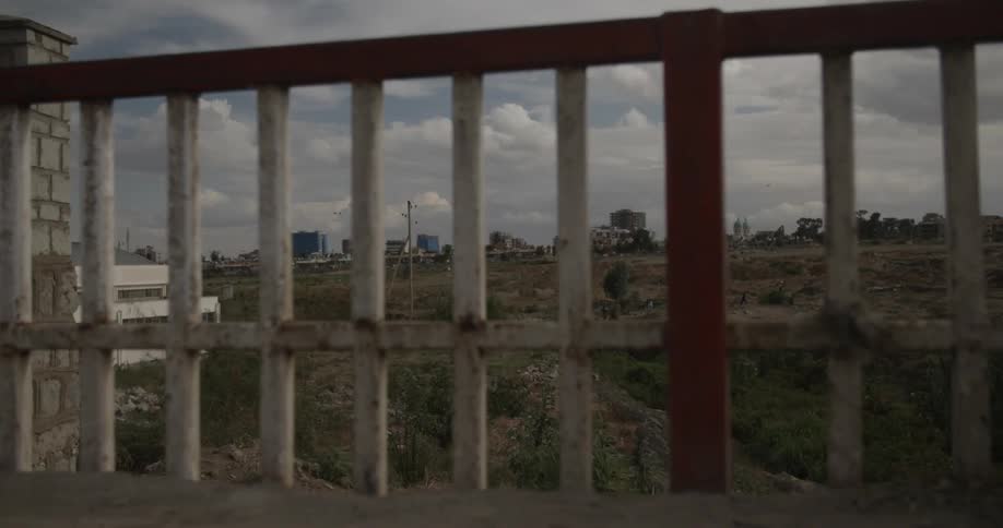 A far away city is shown through a fence