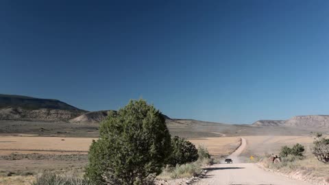 A car comes down a dirt road in the desert