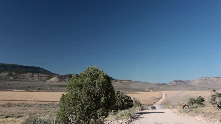 A car comes down a dirt road in the desert