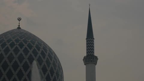 A fountain spouts in front of a domed building