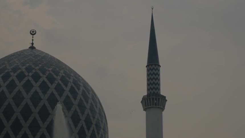 A fountain spouts in front of a domed building