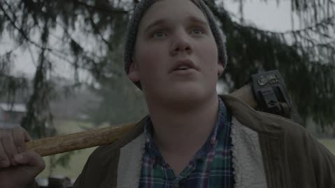 Lumberjack holds axe over his shoulder under the rain