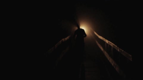 People jogging down a bridge with a flashlight at night