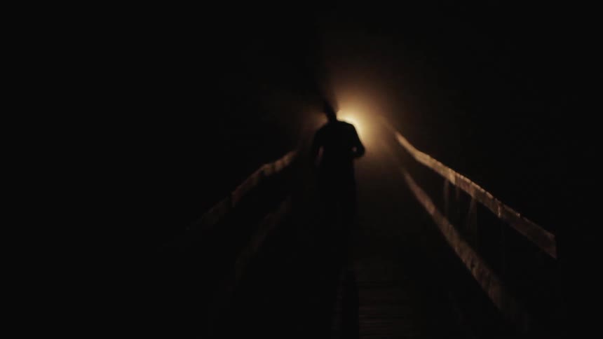 People jogging down a bridge with a flashlight at night