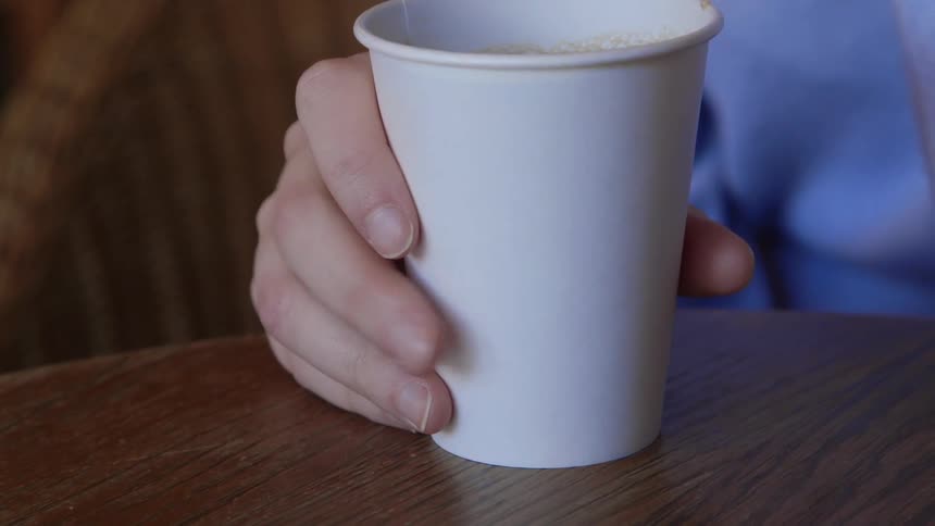 Someone tapping their fingers against a paper coffee cup