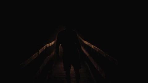 A man walking down a pier on a dark night