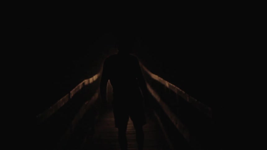 A man walking down a pier on a dark night