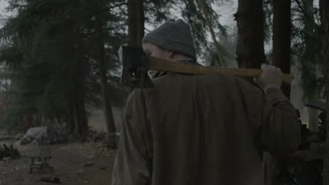 Young man stands with an ax on his shoulder